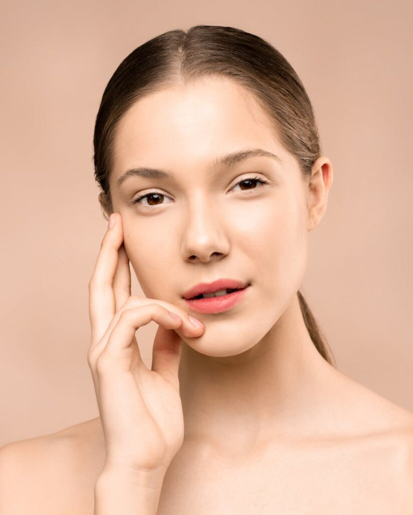Close-up of a woman with flawless skin posing gracefully against a soft background.