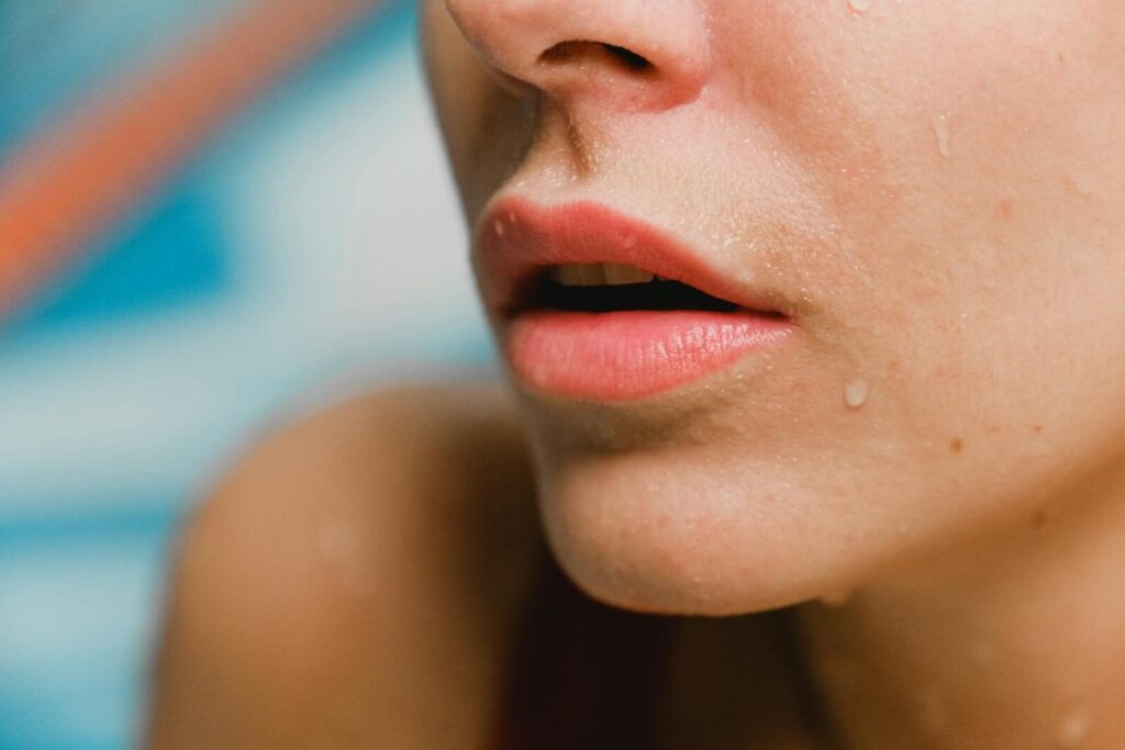 A close-up photo focusing on lips with water droplets on skin, conveying freshness.